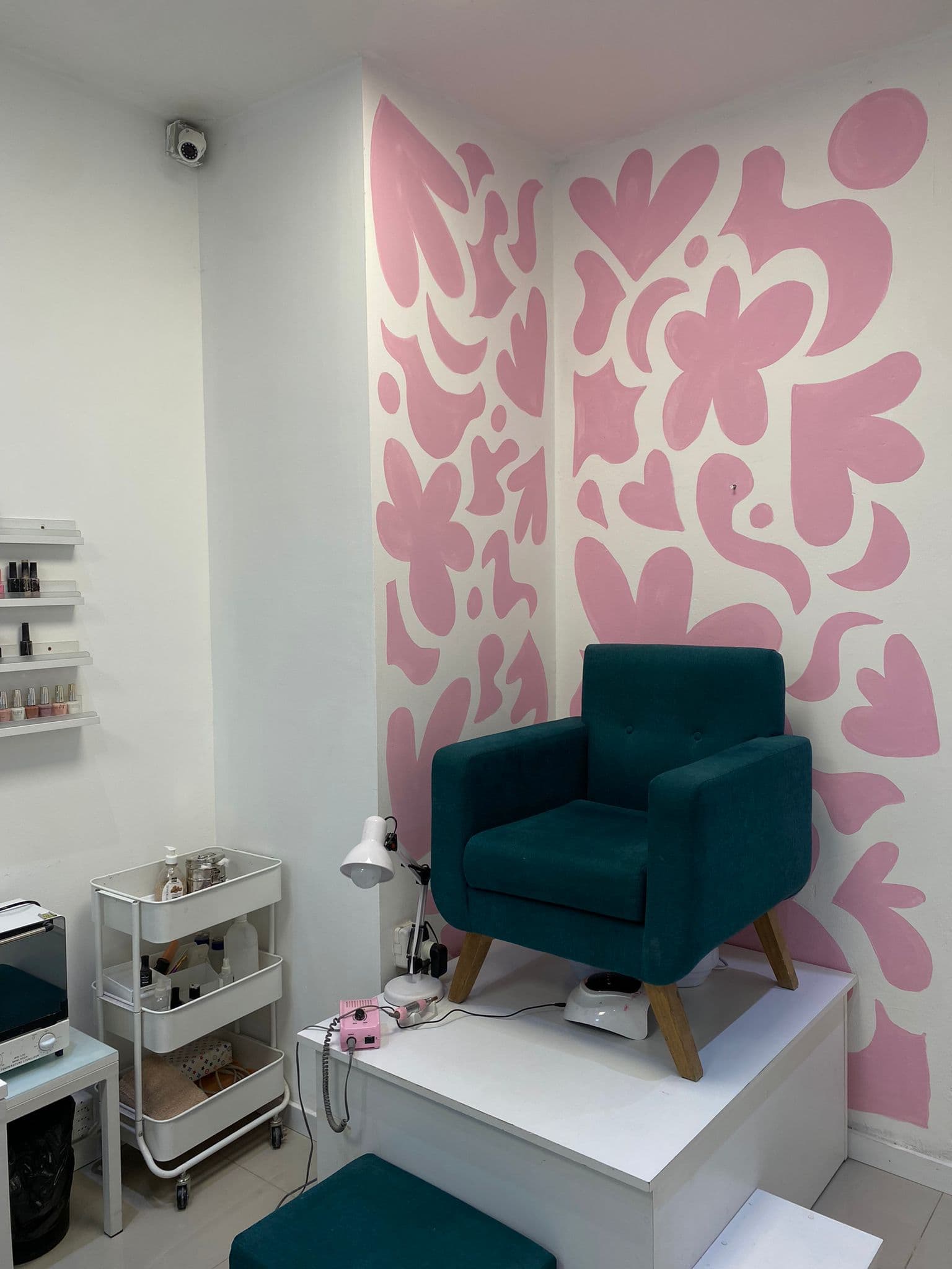 Cabina de pedicura en NIGMA: sillón verde frente al mural rosa floral